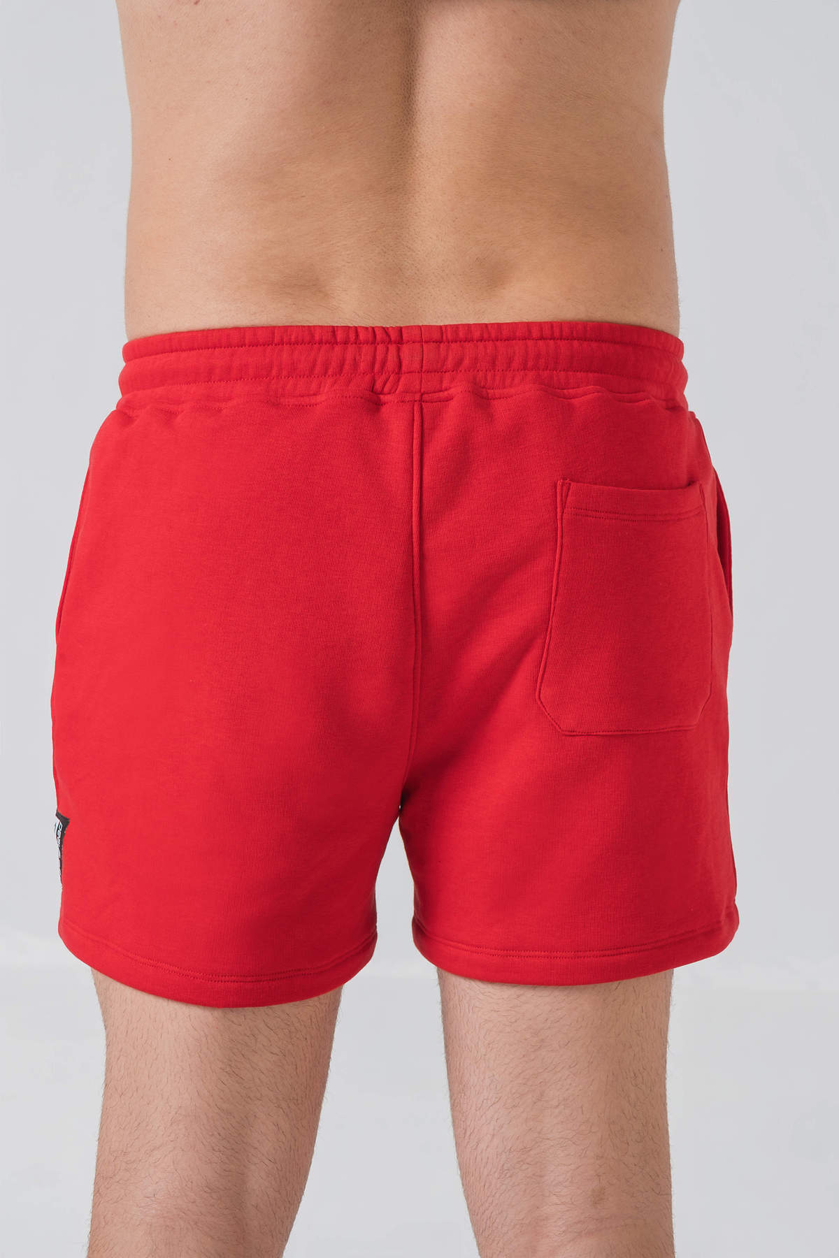 Pantallona të shkurtra District – Pantallona të shkurtra sportive/casual për meshkuj në ngjyrë të kuqe, me brez elastik me spango rregulluese (drawstring), xhepa anësorë, një xhep në pjesën e pasme dhe stemë me logon trekëndëshe Dominer në pjesën e poshtme anësore.