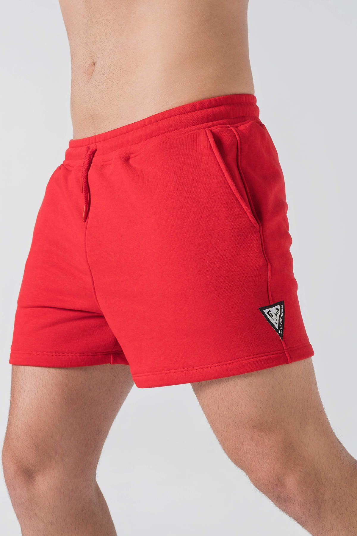 Pantallona të shkurtra District – Pantallona të shkurtra sportive/casual për meshkuj në ngjyrë të kuqe, me brez elastik me spango rregulluese (drawstring), xhepa anësorë, një xhep në pjesën e pasme dhe stemë me logon trekëndëshe Dominer në pjesën e poshtme anësore.