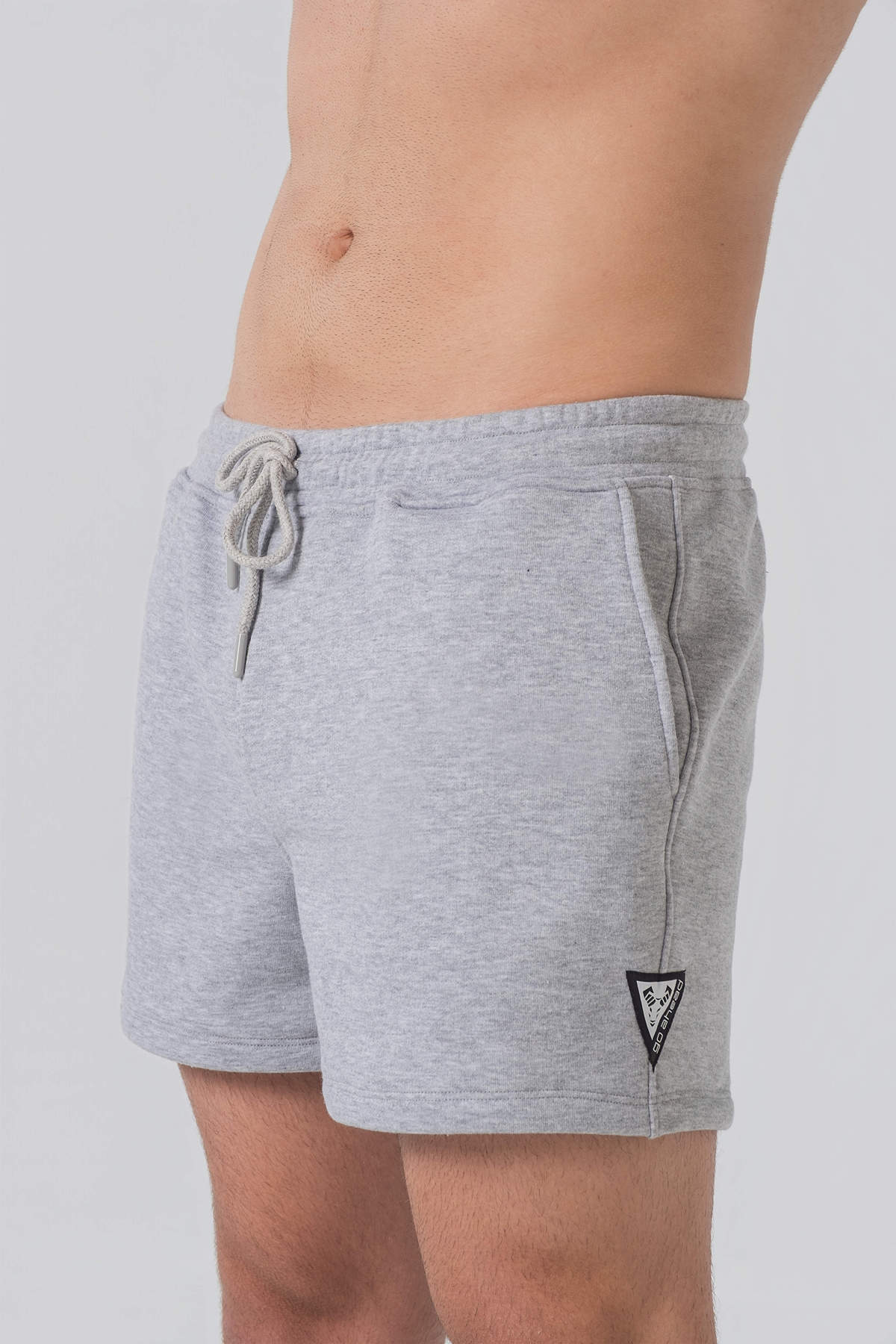 Pantallona të shkurtra District – Pantallona të shkurtra sportive/casual për meshkuj në ngjyrë hiri melanzh (grey melange), me brez elastik me spango rregulluese (drawstring), xhepa anësorë, një xhep në pjesën e pasme dhe stemë me logon trekëndëshe Dominer në pjesën e poshtme anësore.