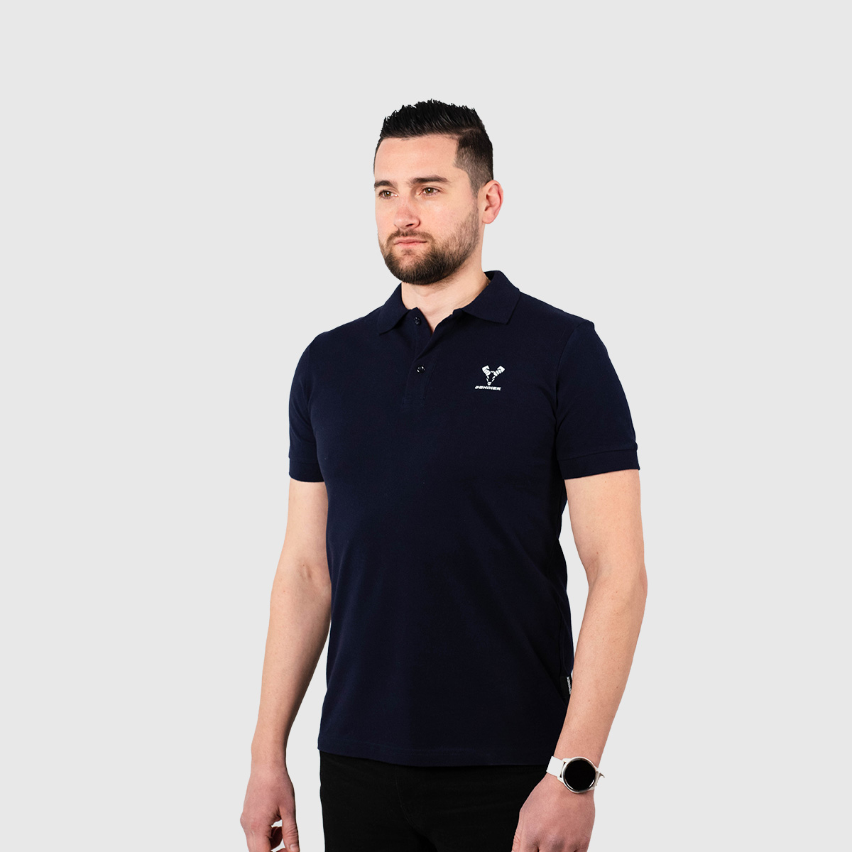 CASUAL Bluze Polo – Bluzë polo për meshkuj në ngjyrë të kaltër të errët (navy), me jakë me kopsa, mëngë të shkurtra me skaje me elasticitet, dhe logon e vogël të bardhë të dhisë Dominer të printuar në gjoksin e majtë.