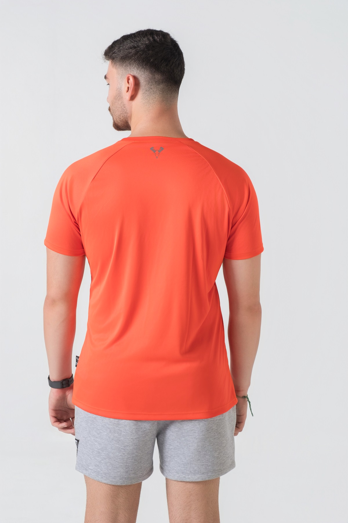 Casual t-shirt SHIFT – Bluzë sportive/casual me mëngë të shkurtra raglan për meshkuj në ngjyrë portokalli të ndezur (coral/orange), me jakë të rrumbullakët, emrin e markës Dominer të printuar në gjoks, logo minimale në pjesën e pasme sipër dhe etikete anësore.