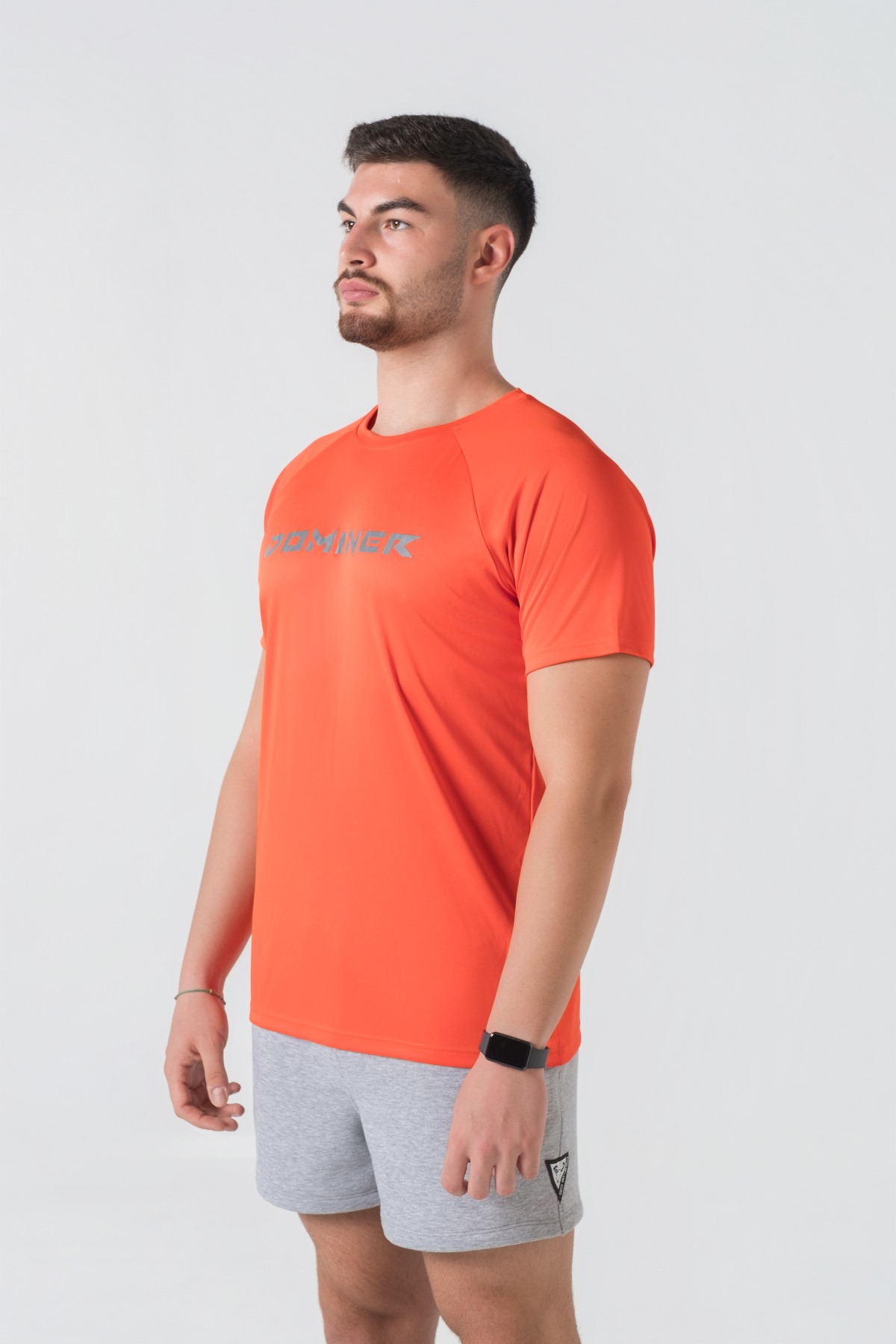 Casual t-shirt SHIFT – Bluzë sportive/casual me mëngë të shkurtra raglan për meshkuj në ngjyrë portokalli të ndezur (coral/orange), me jakë të rrumbullakët, emrin e markës Dominer të printuar në gjoks, logo minimale në pjesën e pasme sipër dhe etikete anësore.