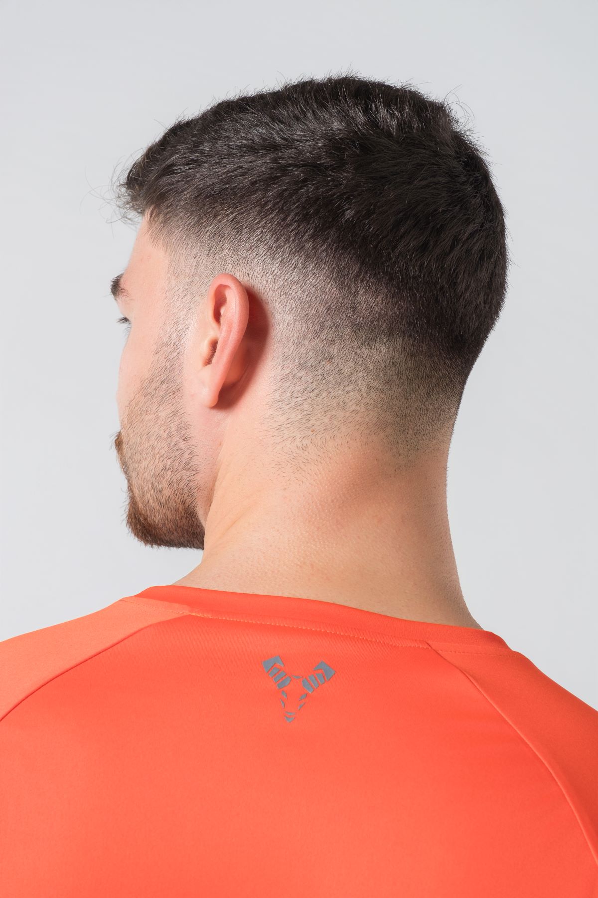 Casual t-shirt SHIFT – Bluzë sportive/casual me mëngë të shkurtra raglan për meshkuj në ngjyrë portokalli të ndezur (coral/orange), me jakë të rrumbullakët, emrin e markës Dominer të printuar në gjoks, logo minimale në pjesën e pasme sipër dhe etikete anësore.