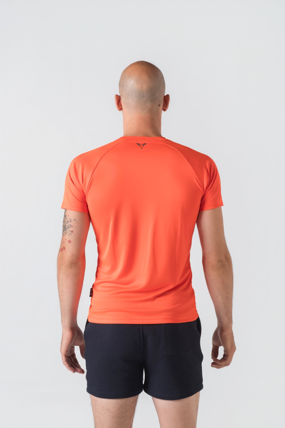 Casual t-shirt SHIFT – Bluzë sportive/casual me mëngë të shkurtra raglan për meshkuj në ngjyrë portokalli të ndezur (coral/orange), me jakë të rrumbullakët, emrin e markës Dominer të printuar në gjoks, logo minimale në pjesën e pasme sipër dhe etikete anësore.