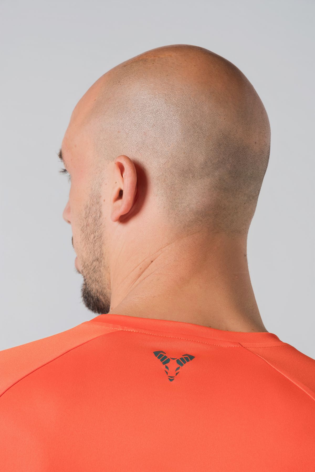 Casual t-shirt SHIFT – Bluzë sportive/casual me mëngë të shkurtra raglan për meshkuj në ngjyrë portokalli të ndezur (coral/orange), me jakë të rrumbullakët, emrin e markës Dominer të printuar në gjoks, logo minimale në pjesën e pasme sipër dhe etikete anësore.