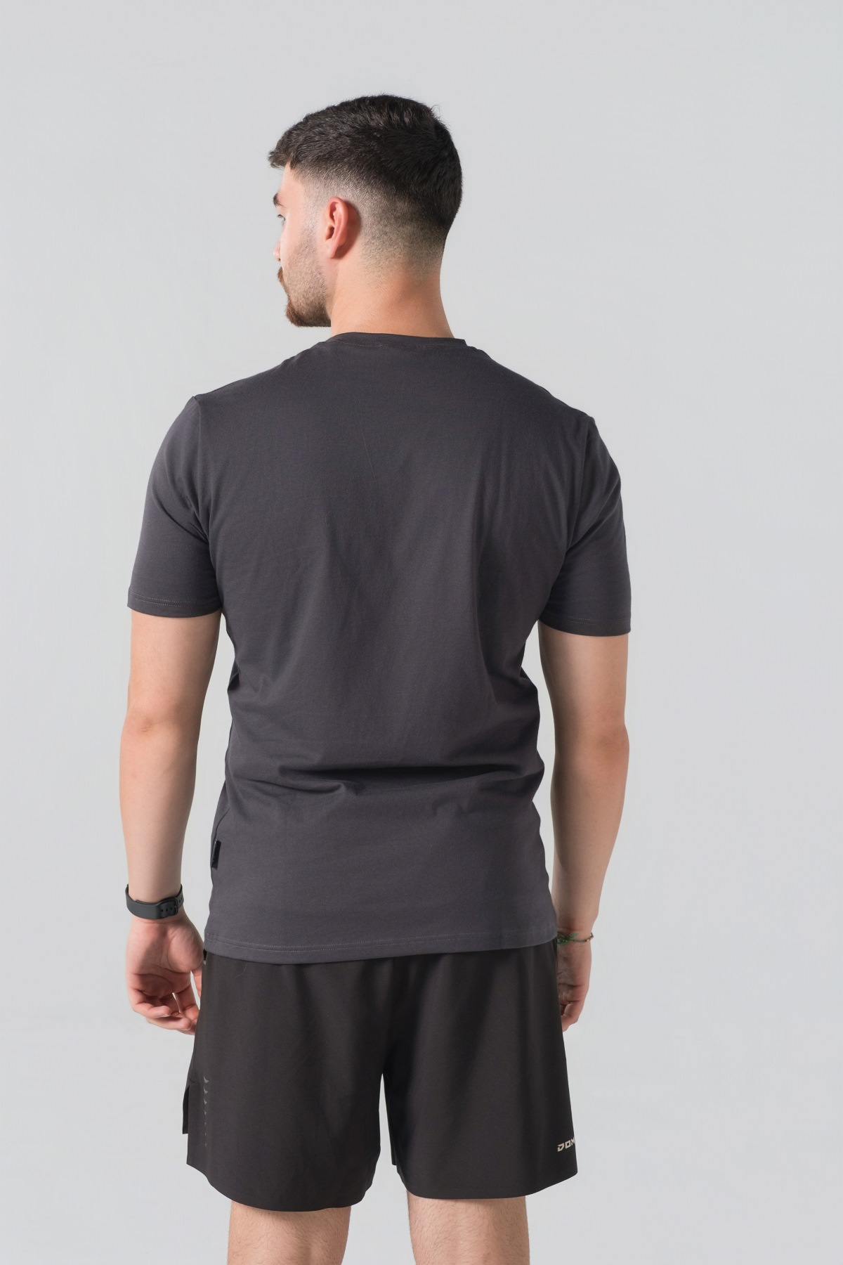 T-shirt Breezy Unisex – Bluzë e thjeshtë me mëngë të shkurtra unisex në ngjyrë hiri të mbyllur (dark grey/charcoal), me jakë të rrumbullakët, print grafik veror detar me anije me vela dhe mbishkrimin "Ocean Adventure / Sail Boat" në ngjyrë të bardhë në gjoks.