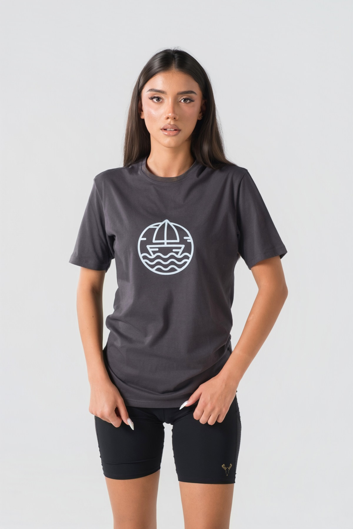 T-shirt Breezy Unisex – Bluzë e thjeshtë me mëngë të shkurtra unisex në ngjyrë hiri të mbyllur (dark grey/charcoal), me jakë të rrumbullakët, print grafik me emblemë rrethore detare me anije/varkë dhe valë deti në ngjyrë të kaltër të çelët në gjoks.