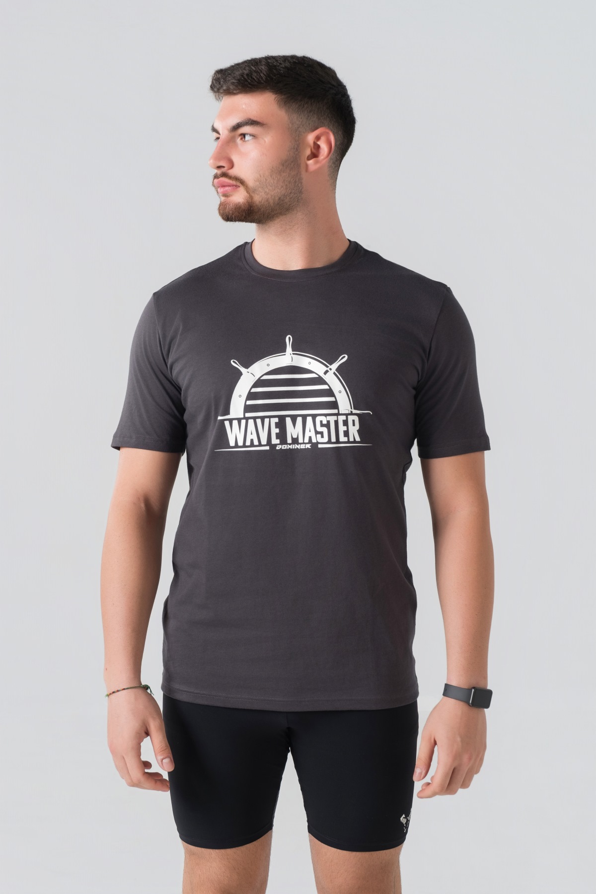 T-shirt Breezy Unisex – Bluzë e thjeshtë me mëngë të shkurtra unisex në ngjyrë hiri të mbyllur (dark grey/charcoal), me jakë të rrumbullakët, print grafik veror detar me timon timonieri dhe mbishkrimin "WAVE MASTER" në ngjyrë të bardhë në gjoks.