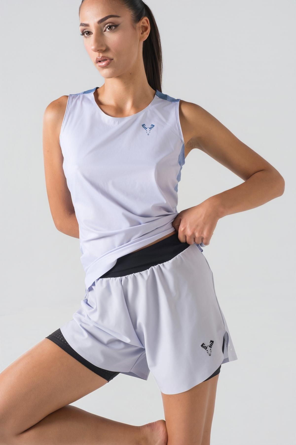 Shift Kanatjere Femrash – Kanatjere sportive për femra në ngjyrë të kjelët (light blue/ice blue), me jakë të rrumbullakët, panel rrjetë (mesh) të shpuar në shpinë dhe pjesët anësore për ajrosje optimale, të çara të vogla anësore në fund, logo minimale Dominer në gjoks dhe emrin e markës të printuar në pjesën e pasme sipër.