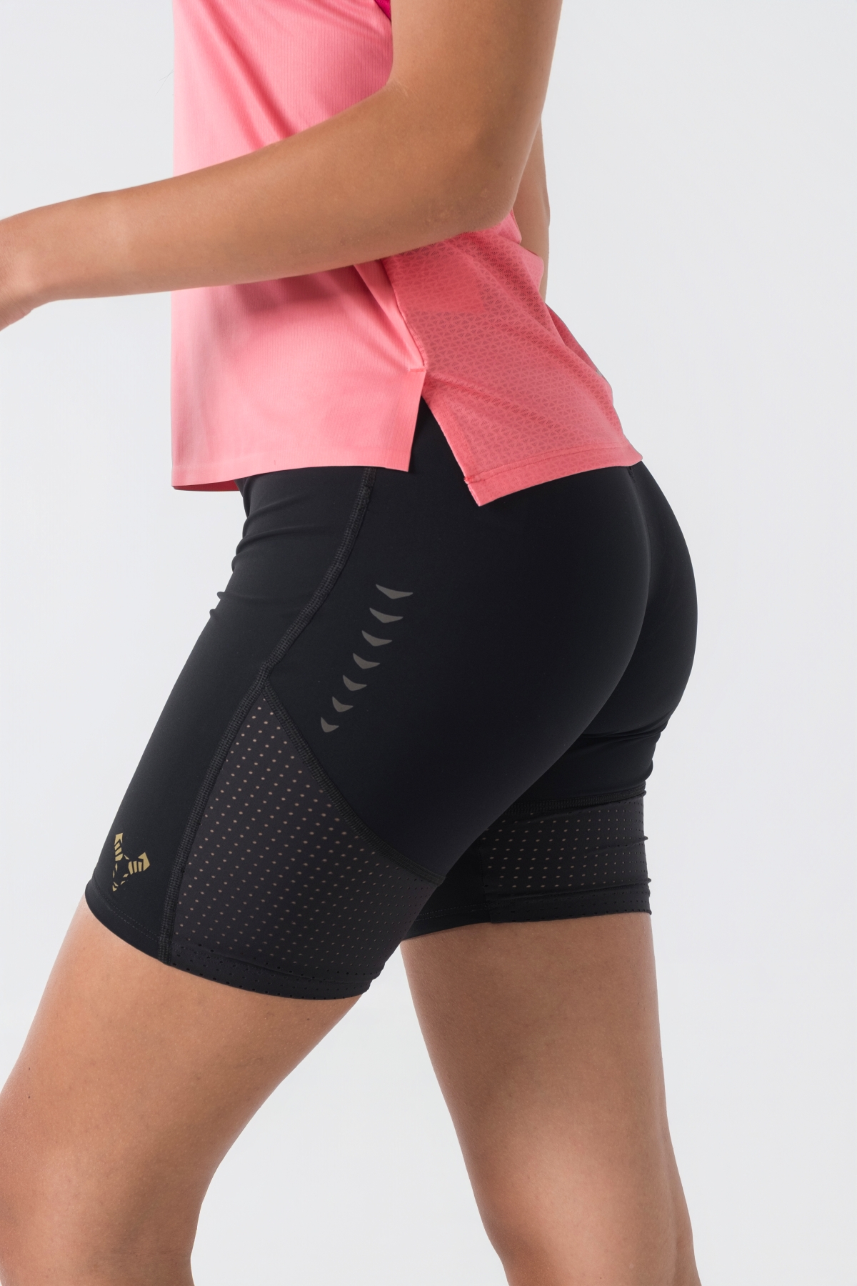 Shift Kanatjere Femrash – Kanatjere sportive për femra në ngjyrë rozë të çelët (coral pink) me panela anësore dhe në shpatulla në ngjyrë rozë më të mbyllur (fuchsia), jakë të rrumbullakët, panel rrjetë (mesh) të shpuar në shpinë për ajrosje, të çara të vogla anësore në fund, logo minimale Dominer në gjoks dhe emrin e markës të printuar në pjesën e pasme sipër.