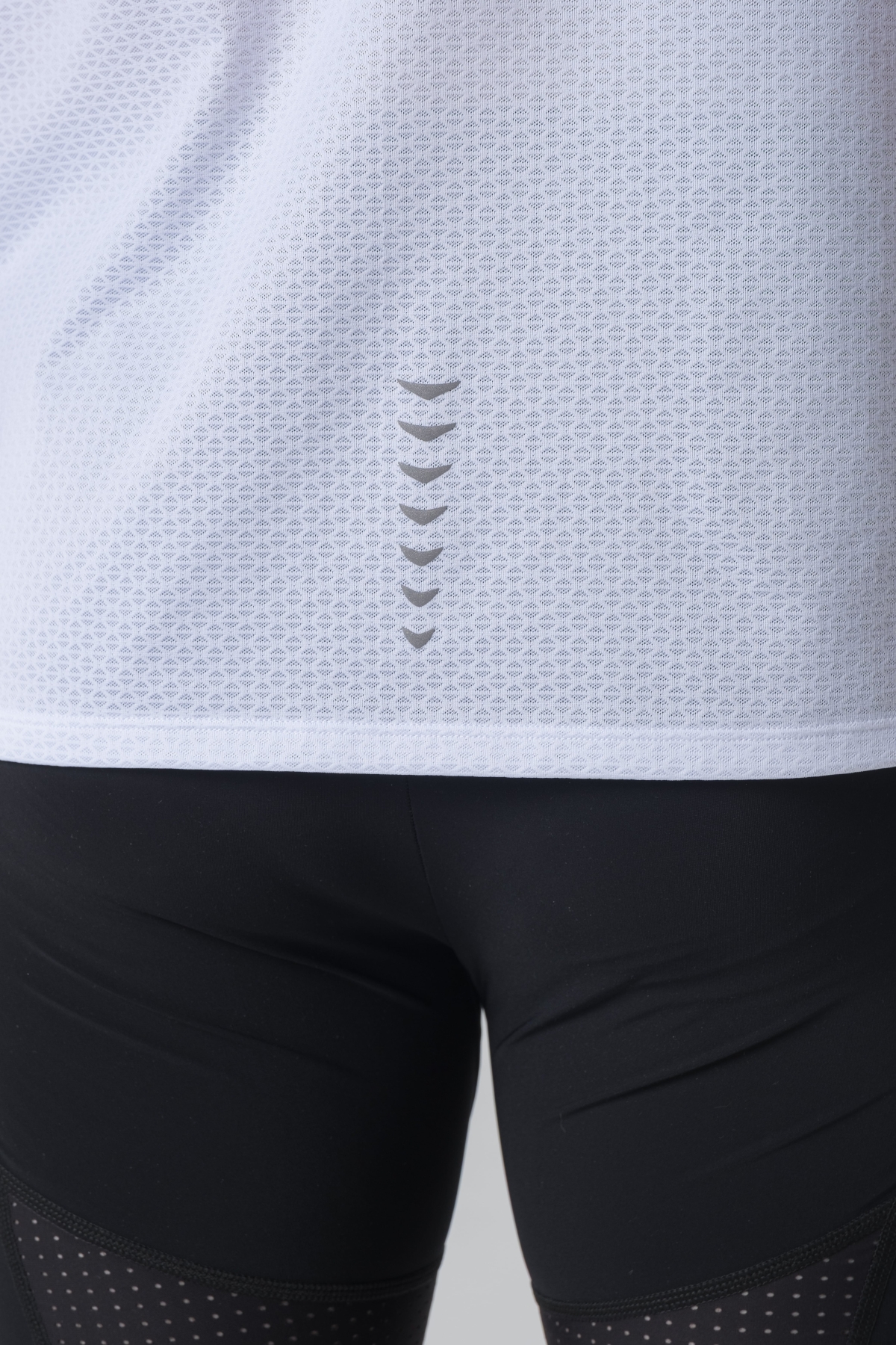 Shift Bluze Meshkujsh – Bluzë sportive me mëngë të shkurtra për meshkuj në ngjyrë të bardhë, me jakë të rrumbullakët, material me teksturë rrjetë për ajrosje, logo minimale Dominer në gjoks, emrin e markës të printuar në pjesën e pasme sipër dhe detaj vertikal me shigjeta në pjesën e poshtme prapa.