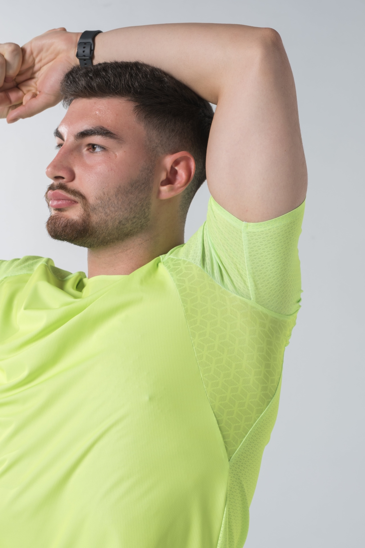 Shift Bluze Meshkujsh – Bluzë sportive me mëngë të shkurtra për meshkuj në ngjyrë të verdhë me neoni (lime green/yellow), me jakë të rrumbullakët, material me teksturë rrjetë (mesh) prapa dhe në mëngë për ajrosje, të çara të vogla anësore në fund, logo minimale Dominer në gjoks dhe emrin e markës të printuar në pjesën e pasme sipër.