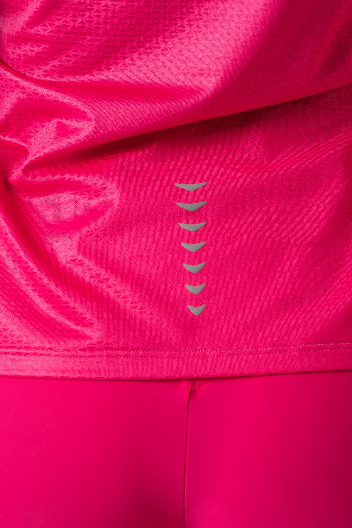 Shift Bluze Femrash – Bluzë sportive me mëngë të shkurtra për femra në ngjyrë rozë elektrike (pink/fuchsia), me jakë të rrumbullakët me detaj rozë më të çelët, material me teksturë rrjetë (mesh) në shpinë, mëngë dhe panela anësore për ajrosje, të çara të vogla anësore në fund, logo minimale Dominer në gjoks dhe emrin e markës të printuar në pjesën e pasme sipër.